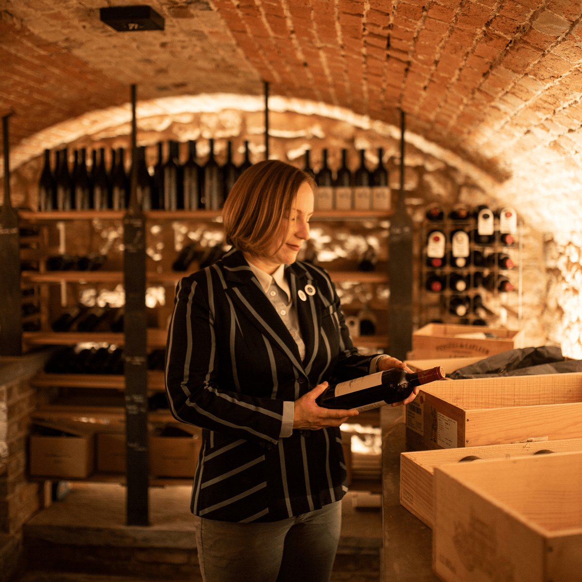 Woman holding bottle of wine in cellar | True Grace Louise Gordon article